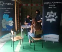 przy stoisku promocyjnym policjanci rozmawiają z uczennicą - absolwentka liceum