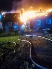 Palący się dom i strażacy gaszący go