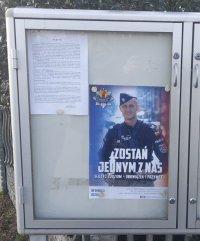 Na tablicy informacyjnej widać plakat promujący służbę w Policji, z wizerunkiem umundurowanego funkcjonariusza.