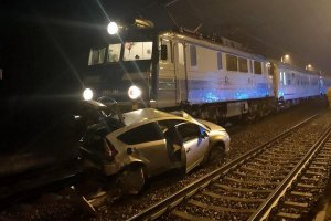 Na torach stoi pociąg który uderzył w samochód koloru srebrnego, auto jest uszkodzone