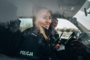 W radiowozie siedzi umundurowana policjantka i policjant.