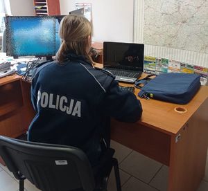w pomieszczeniu służbowym umundurowana policjantka siedzi przy biurku na którym stoi odzyskany laptop