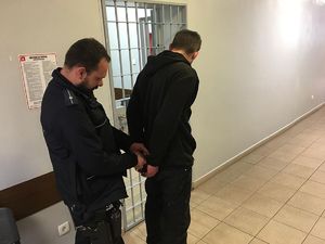 w areszcie umundurowany policjant zakłada zatrzymanemu kajdanki