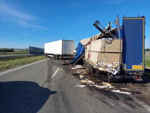 wypadek na drodze s-8, na pasie drogowym stoją uszkodzone ciężarówki,  widać porozrzucany towar i elementy karoserii