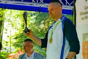 na podium stoi asp. sztab. Bogdan Tułacz, trzyma w dłoni puchar