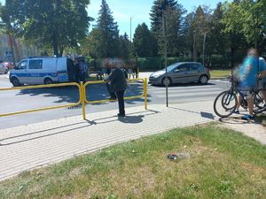 na poboczu stoi oznakowany radiowóz obok stoją policjanci i mężczyzna niedaleko  stoi szary peugeot