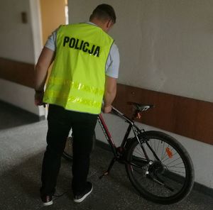 policjanci ubrany w kamizelkę odblaskową prowadzi oględziny roweru