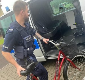 umundurowany policjant wprowadza odzyskany rower do radiowozu