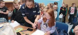 umundurowana policjantka wykonuje dzieciom odciski palców
