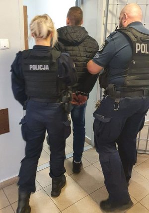 z policyjnego aresztu wychodzi zatrzymany prowadzony przez dwóch umundurowanych policjantów
