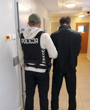 na korytarzu aresztu policjant prowadzi zatrzymanego