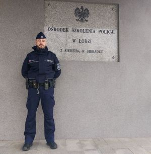 Przed budynkiem Ośrodka Szkolenia Policji w Łodzi z /s w Sieradzu stoi umundurowany policjant.