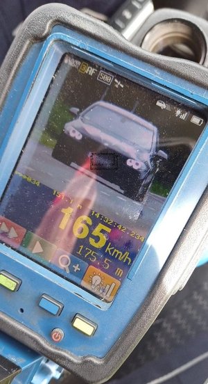 Zdjęcie z urządzenia do pomiaru prędkości, widać jadący z naprzeciwka czarny samochód oraz prędkość 165 km/h.