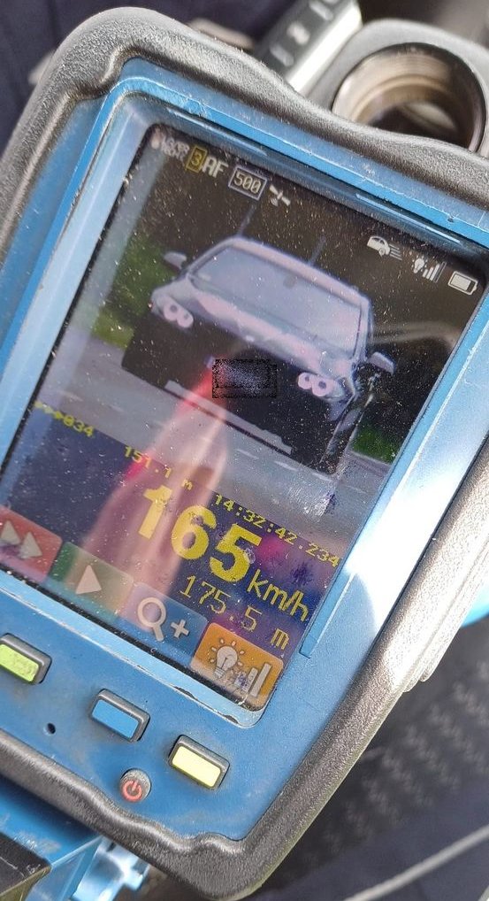 Zdjęcie z urządzenia do pomiaru prędkości, widać jadący z naprzeciwka czarny samochód oraz prędkość 165 km/h.