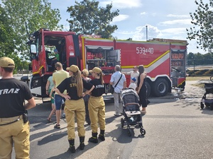 Piknik przed budynkiem komendy, rozstawione są namioty wystawców, pojazdy służb mundurowych, osoby odwiedzają stoiska.