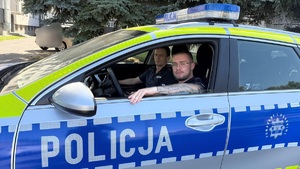 W oznakowanym radiowozie siedzi siedzi dwóch umundurowanych policjantów.