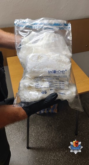 Policjant trzyma w dłoniach worek foliowy z narkotykami.