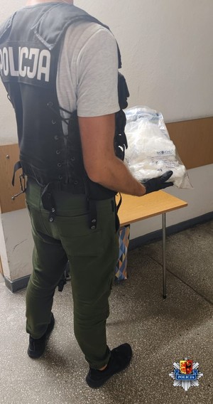 Policjant trzyma w dłoniach worek foliowy z narkotykami.