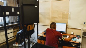 Technik kryminalistyki wykonuje zdjęcia sygnalityczne zatrzymanej kobiecie.