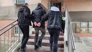 Po schodach policyjnego aresztu nieumundurowani policjanci prowadzą zatrzymanego mężczyznę.