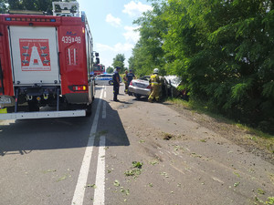 Policjanci wraz ze Strażą Pożarną zabezpieczają miejsce zdarzenia drogowego.
