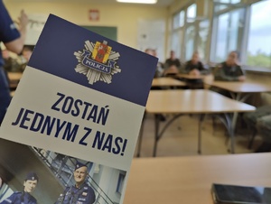 Ulotka Zostań Jednym z Nas!, w tle siedzą słuchacze prelekcji.
