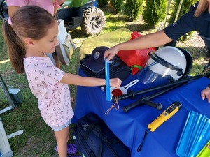 Policjantka zakłada dziewczynce opaskę odblaskową.