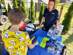 Chłopczyk ogląda policyjne stoisko, w tle stoi policjantka.