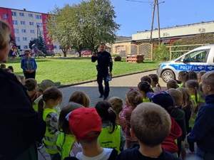 Policjant pokazuje dzieciom sygnalizator świetlny.