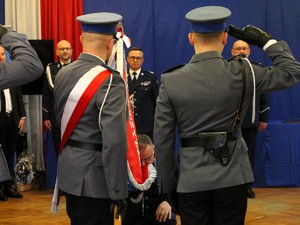 Komendant Powiatowy Policji w Łasku żegna się ze sztandarem jednostki. Poczet sztandarodwy oddaje honor. W tle widać Komendanta Wojewódzkiego Policji w Łodzi.