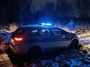 Policyjny radiowóz i stojący przy nim policjant.