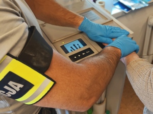 Policjant pobiera odciski palców od zatrzymanego.