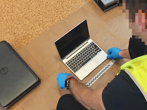 Policjant wykonuje oględziny laptopa.