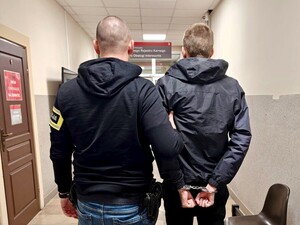 Policjant trzyma zatrzymanego.