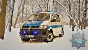 radiowóz oznakowany na tle zimowej scenerii  w dolnym, prawym roku gwiazda policyjna z napisem Łęczyca.