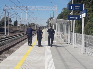 strażnicy ochrony kolei wraz z policjantka idą po peronie.