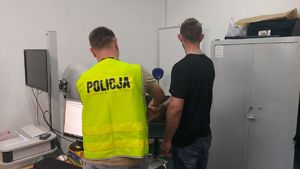 Policjant z zatrzymanym stoją tyłem.