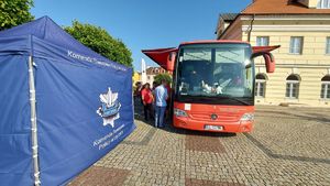 Mobilny Punkt Poboru na placu Kościuszki , obok namiot Komendy Powiatowej Policji w Łęczycy i stojące osoby.