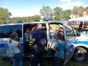 Dzieci z policjantem przed radiowozem na pikniku rodzinnym w Łęczycy.