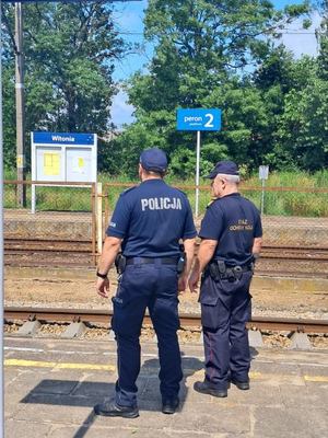 Policjant wraz z funkcjonariuszem ochrony kolei kontrolują infrastrukturę kolejową.