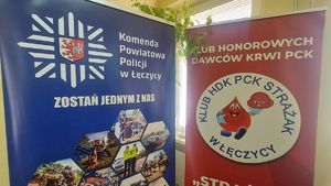Zdjęcie niebieskiego baneru policji z czerwonym banerem klubu honorowych dawców krwi.