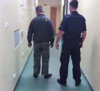 Policjant z zatrzymanym na korytarzu.