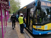 Policjantka z Ruchu Drogowego wraz z funkcjonariuszem Straży Miejskiej udają się do autobusu miejskiego, który stoi na przystanku autobusowym na kontrole