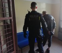 policjant wprowadza do pomieszczenia zatrzymanego