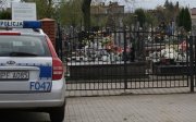 radiowóz policyjny zaparkowany na parkingu przed cmentarzem.