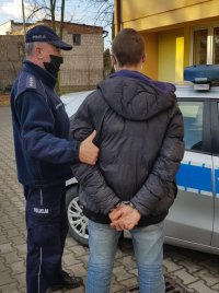 Policjant stoi z zatrzymanym sprawcą