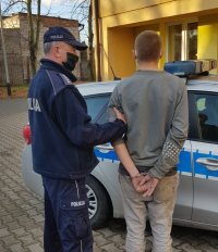 Policjant stoi z zatrzymanym sprawcą