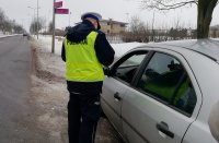 policjant z Ruchu Drogowego stoi przy samochodzie od strony kierowcy, dokonuje kontroli dokumentów