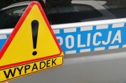 trójkąt żółty ostrzegawczy z napisem wypadek na tle niebieskiego napisu Policja