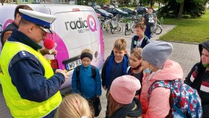 parking przed szkoła policjant rozdaje odblaski,